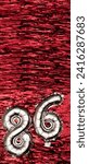 Small photo of Silver foil balloon number 86 on a background of red tinsel decoration. Birthday greeting card, inscription eighty-six. Anniversary event. Vertical Banner. copy space.