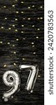 Small photo of Silver foil balloon number ninety-seven. Birthday or anniversary card with the inscription 97. Black tinsel background. Anniversary celebration. Vertical Banner. copy space