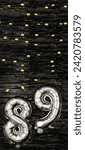 Small photo of Silver foil balloon number eighty-nine. Birthday or anniversary card with the inscription 89. Black tinsel background. Anniversary celebration. Vertical Banner. copy space