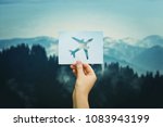 Hand holds a paper with plane icon over silent nature background. Love travel concept. Flight restrictions due coronavirus COVID-19 pandemic outbreak. Only charter flight allowed. Quarantine concept.
