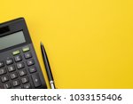 Flat lay or top view of black pen with calculator on vivid yellow background table with blank copy space, math, cost, tax or investment calculation.