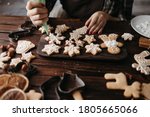 Christmas, New Year, DIY, holidays preparation and creativity concept. Getting ready to celebration. Woman hands decorating homemade gingerbread cookies with icing
