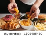 Unhealthy snack, junk food, compulsive overeating. Man overeating unhealthy meals taking hamburger and potato chips from plate