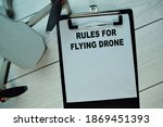 Rules For Flying Drone write on a paperwork isolated on Wooden Table.