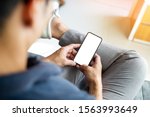 Mockup image blank white screen cell phone.men hand holding texting using mobile relax on sofa at home. background empty space for advertise text.people contact marketing business and technology 