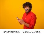 Small photo of Funny surprised trendy guy suddenly read message on his mobile phone and expressing shock amazement, unbelievable news on smartphone. Studio shot isolated