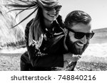 Black&white photo of happy couple in the leather jackets running on the beach