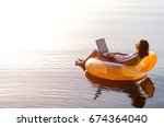 Business woman working on a laptop in an inflatable ring in the water, a copy of the free space. Workaholic, work on vacation.