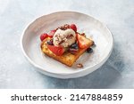 Small photo of Brioche French toast with fresh berries, pecan nuts and ice cream over light blue background. Healthy delicious breakfast. Side view, copy space