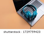 Photo of stylish modern computer or notebook and blue cyan headphones over beige background. Close-up.