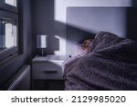Small photo of Sleeping woman in bed at night in dark bedroom. Person resting. Asleep under cover and blanket. Cold room at home. Tired lady in peaceful dream. Blue moonlight from window. Sick with flu.