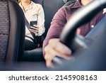 Phone in car or taxi. Passenger woman using cellphone in back seat of cab. Driver and customer. Rideshare mobile app. Professional business person travel to work, commute. Lady sitting in the backseat