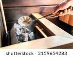 Sauna in Finnish spa. Hot steam, water on stones. Man in wellness and health room in Finland. Warm temperature bath therapy. Traditional summer cabin relaxation.