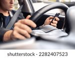 Small photo of Texting and driving a car. Using mobile phone in traffic. Distracted driver, accident or crash. Irresponsible man typing sms text message with cellphone in city road or highway. Steering wheel.