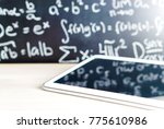 Modern education and e learning concept. Tablet in front of a blackboard full of writing at school. Smart mobile device and chalkboard in classroom. Learning with technology. Digital exam.