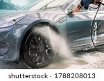 Car washing outdoors. Car washing with soap and high pressure water. Wheel alloy cleaning at car wash station with foam and high pressure water jet. Washing rims