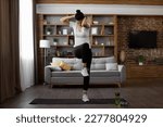 Small photo of Active young brunette in sport clothes standing on yoga mat and making criss cross crunches exercise. Multiracial healthy woman training abs during domestic workout.