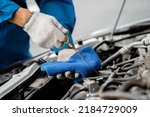 Small photo of Close-up, a car mechanic checking the oil in a car's engine. Technician inspecting and maintaining the engine of a car or vehicle. Female car mechanic checking car engine