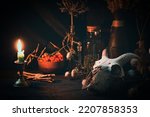 Small photo of Samhain night. Witchs altar with goats skull, burning candle, dry herbs and magic vessels in the dark, low key, selective focus. Halloween, rite, voodoo, occultism, alchemy, spell, paganism concept