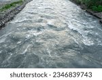 Small photo of Close-up abstract texture above view of river torrent and clear fresh cold water flowing through mountain rocks in valley with foam and bubbles on sunny day. Nature force and power background