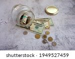 Small photo of Dollars danknotes and coins from all over the world in a glass jar. Unspent small coins brought from travels in different countries.