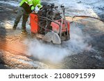 Asphalt saw cutting machine being used in winter with smoke