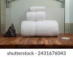 Small photo of A billowing cloud of white towels sits proudly on a smooth wooden surface. The edges of each towel are folded inwards, creating a crisp and uniform appearance. The pile boasts a soft texture, hinting