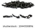 Small photo of a few tea leaves on a blurred pile of dry tea leaves background, large leaf black Bayh tea front view, short focus. on white