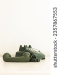 Small photo of Vertical view of vintage olive green rotary phone with receiver unhooked set on pale background