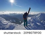 Ski mountaineer standing on top of mountain watching sun and blue sky on beautiful winter day with fresh snow, popular adrenaline activity, Krkonose Mountains National Park, Czech Republic