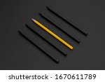 Yellow pencil among black pencils on the matte black background. Minimal style. Conceptual minimalist black art. Matte surface. Office supplies