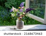 Small photo of Bouquet of wild flowers in a vase on a wooden window sill. Still life on the window of an old country house, summer cottage. Floral home decoration.