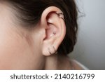 Small photo of Stretched lobe piercing, grunge concept. Pierced woman ear with black plug tunnel. industrial and rook.