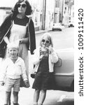 Small photo of Monochrome vintage 1970s mother with daughter and son running errands.