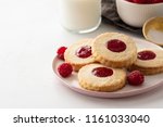 Christmas cookies. Linzer cookies with raspberry jam on white table background. Traditional Austrian biscuits filled. Top view and copy space