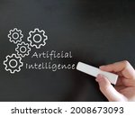 A hand holding a chalk, writing Artificial Inteligence