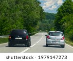 Small photo of A vehicle overtakes near a dangerous curve. There are road signs on the side of the road indicating a dangerous curve. Romania, Severin. May, 22, 2021