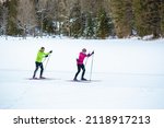 Middle aged couple, cross country skiers, standing on a ski trail and looking at incredible snow mountain peaks.