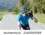 Male cyclist drinking water from bottle during high-intensity pedaling, tracking shot.