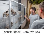 Small photo of Boy having fun in the natural history museum, acting as a curator, and explaining exhibited artifacts to his friends. Concept of museum experience.