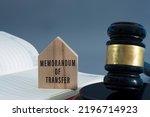 Small photo of Judge gavel with memorandum of transfer text on wooden house on white background.