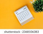 Small photo of January 2024 desk calendar on yellow background. Directly above. Flat lay. Copy space.