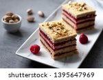 Small photo of Pistachio biscuit layered cake with fresh raspberry, square pieces, grey concrete background, nordic style