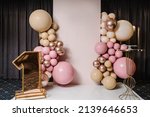 Arch decorated with pink, brown, and gold balloons. Copy space. Birthday arch for 1 year and a background photo wall. Reception at a birthday party.