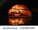Small photo of A traditional oven for cooking and baking pizza with a shovel. Firewood burning in the oven. Wood-fired oven