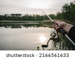 Small photo of Fishing for pike, and perch from a lake or pond. Background wild nature. Fisherman with rod, spinning reel on the river bank. Wild nature. The concept of a rural getaway. Article about fishing day.