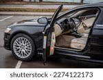 Small photo of Side view of the open driver's door, mirror, dashboard of the car. Left front door. A new modern shiny parked black car. Interior luxury car with tinted glass standing at parking. Modern car exterior.