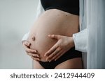 Small photo of Closeup belly of a woman. Pregnancy motherhood procreation concept. Pregnant woman. Female waiting for newborn baby. Young pregnant girl touching and holding her belly and caring about health indoors.