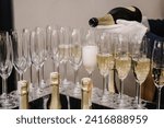 The waiter pouring white sparkling wine. Catering service concept. Barmen pours champagne into flute glasses. Champaign is being poured into glasses. Bottle in a closeup view. Rows of full glasses.