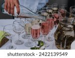 The waiter woman pouring sparkling wine. Catering service concept. The female pours champagne into flute glasses. Champaign is being poured into glasses. Bottle in a closeup view. Rows of full glasses